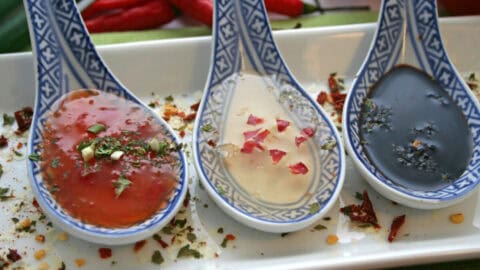 A tray of different Asian sauces on spoons.
