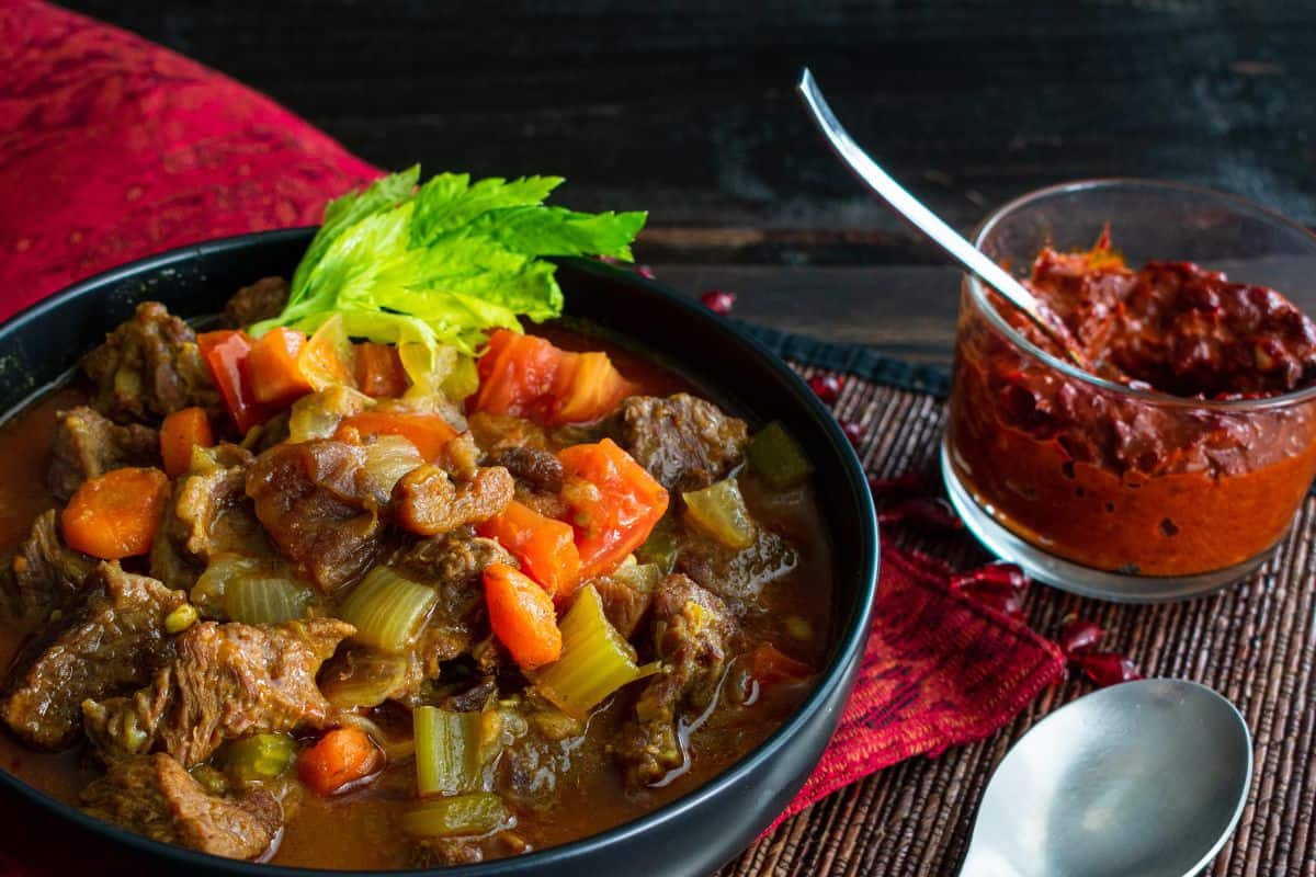 A bowl of moroccan beef stew with harissa sauce.