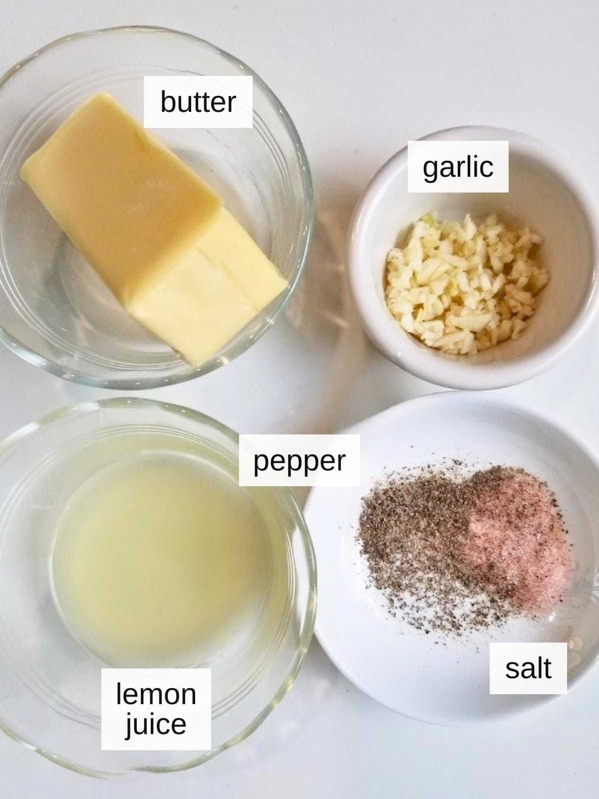 Ingredients for lemon butter sauce, including raw garlic, butter, black pepper, salt, and lemon juice.