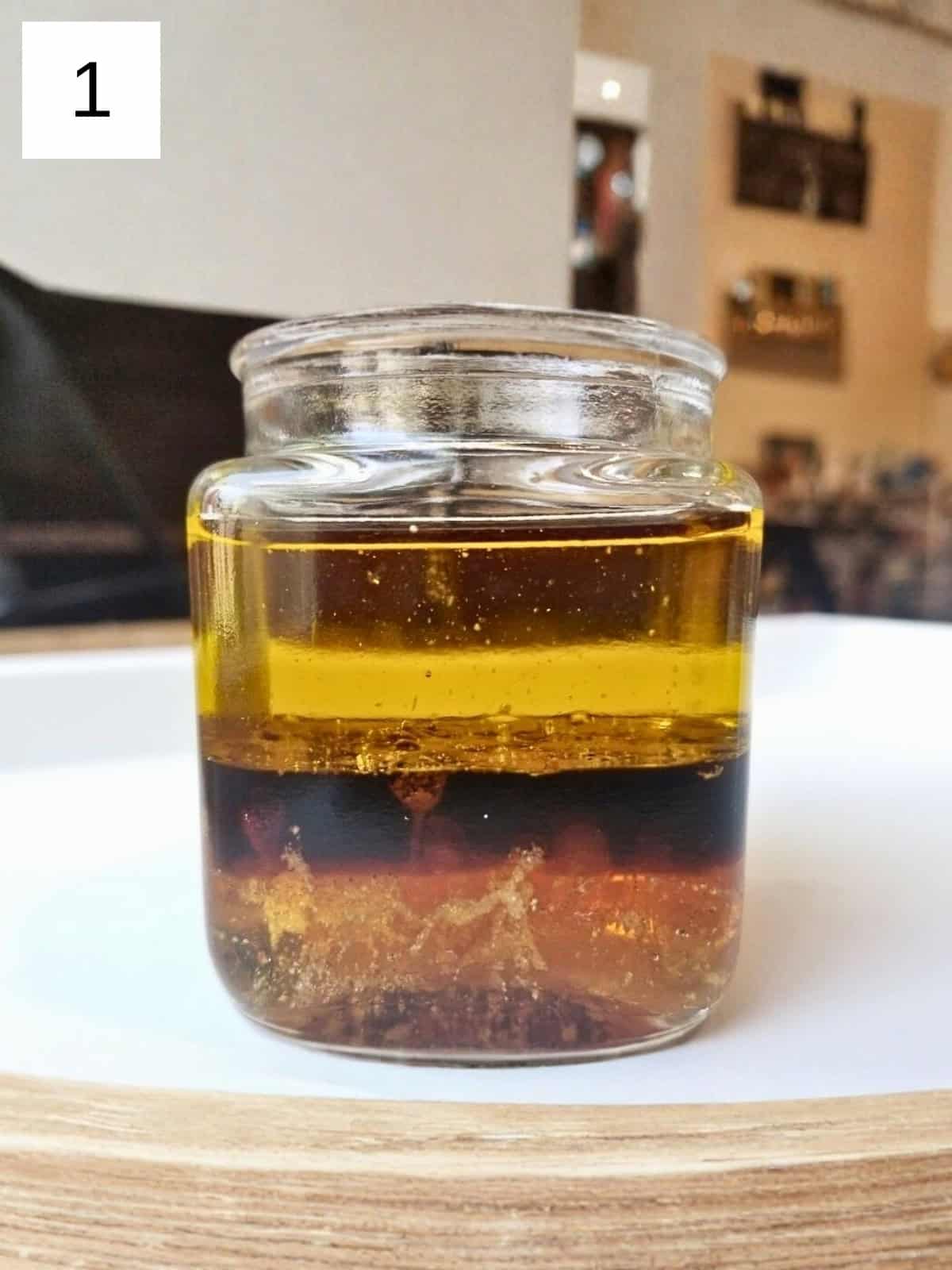 Ingredient for honey balsamic dressing, including honey, balsamic vinegar, salt, garlic powder, and oil. in a glass container.