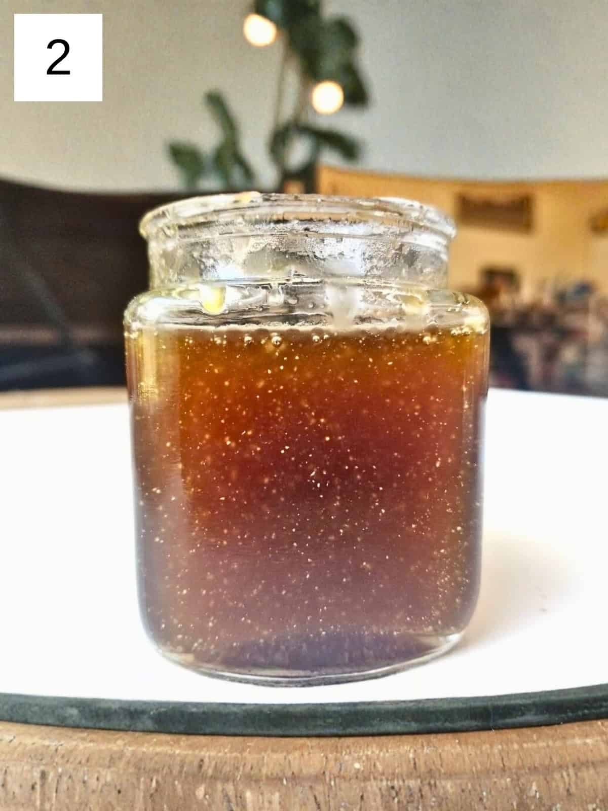 A mixture of honey balsamic dressing in a glass container.
