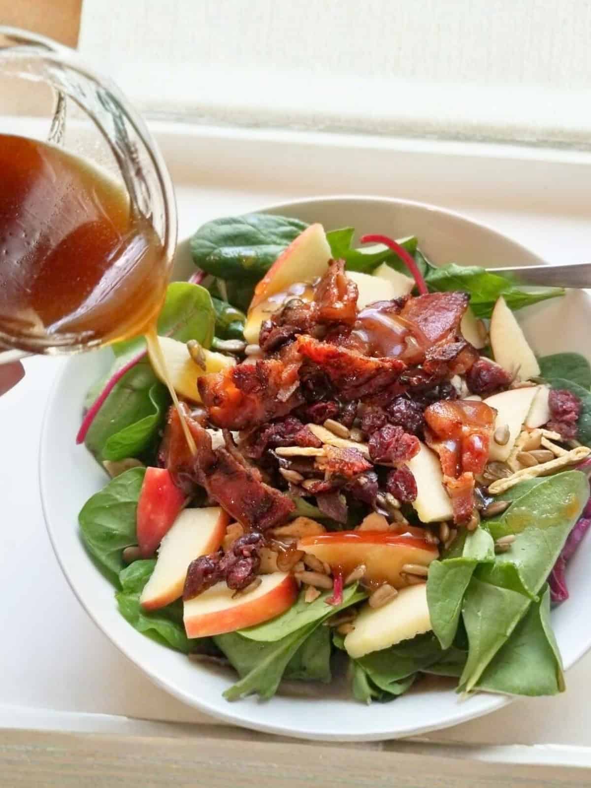 A plate of salad, topped with honey balsamic dressing.
