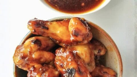 A bowl of roasted chicken pieces with honey sriracha sauce.