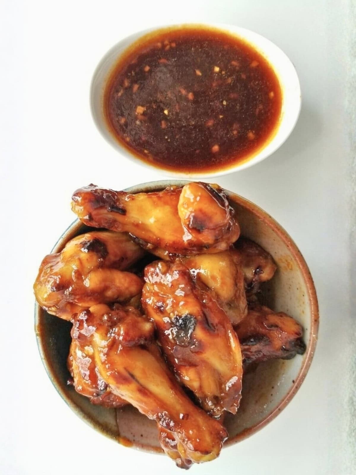 A bowl of roasted chicken pieces with honey sriracha sauce.