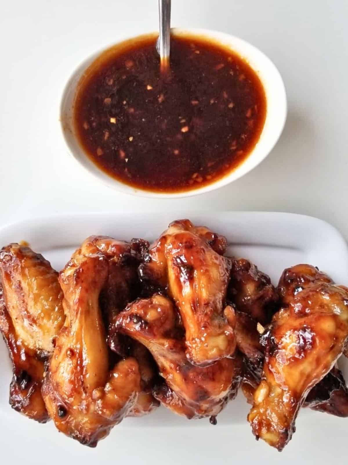 A bowl of roasted chicken pieces with honey sriracha sauce.