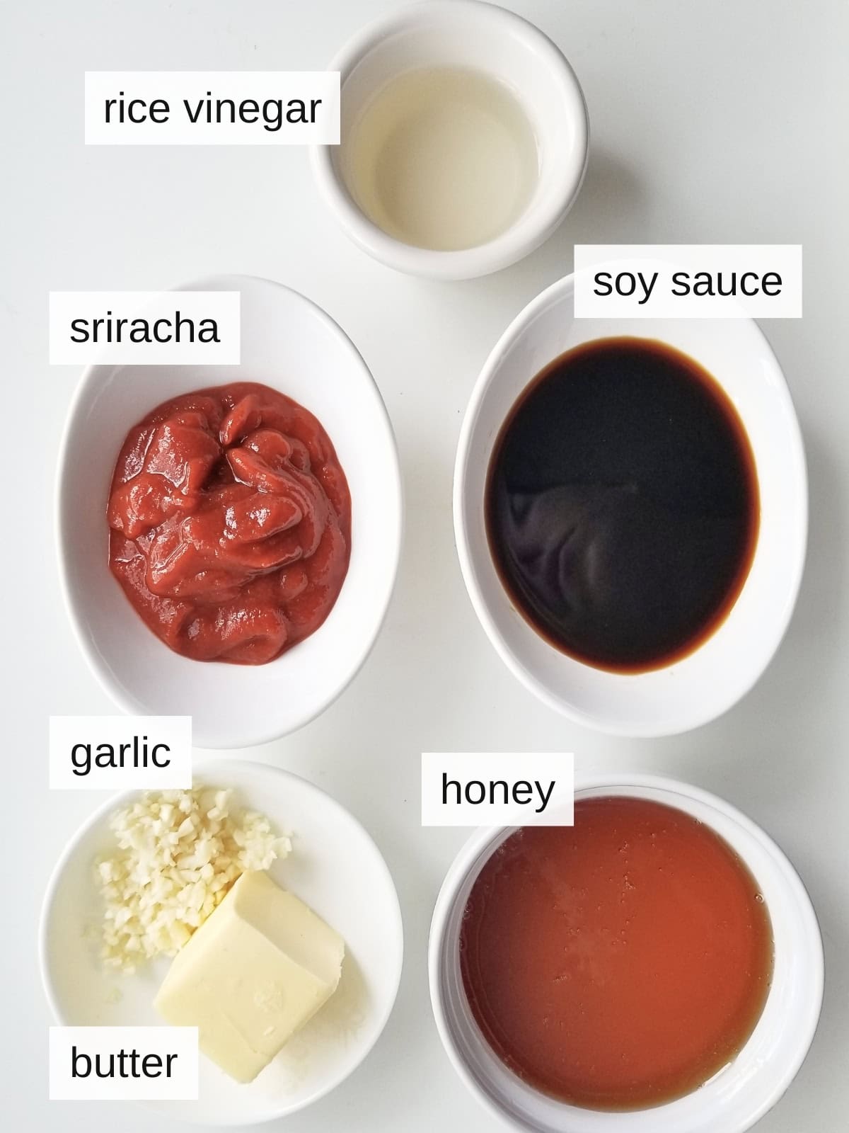 Ingredients for honey sriracha sauce, including rice vinegar, soy sauce, sriracha, fresh garlic, butter, and honey.