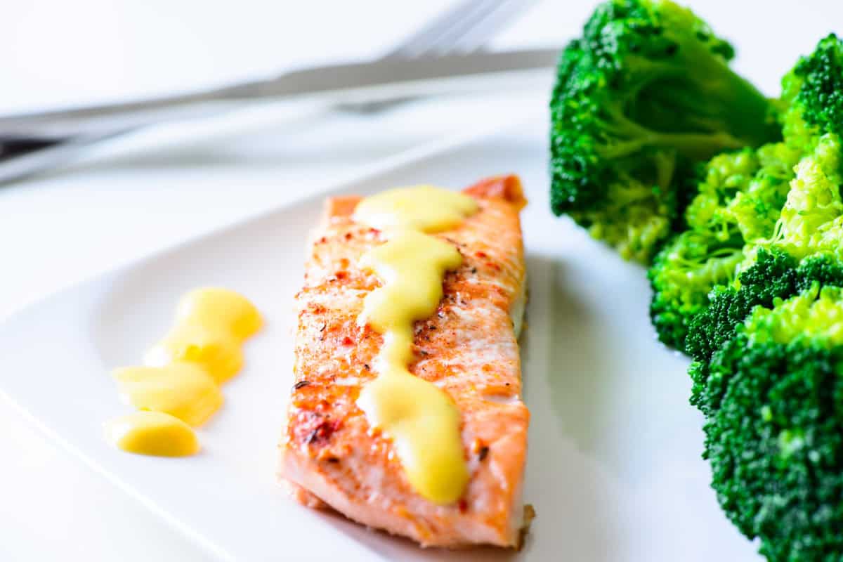 Freshly cooked salmon, topped with hollandaise sauce, in a plate.