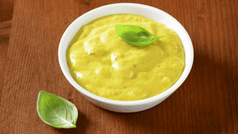 A bowl of curry sauce, topped with fresh leaf.