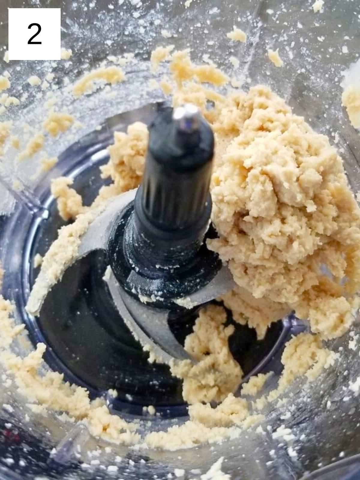 A blended mixture of tahini and lemon juice in a food processor.