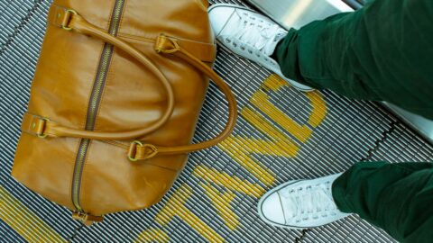 Stylish brown leather duffel bag and white sneakers at Seoul transport hub.
