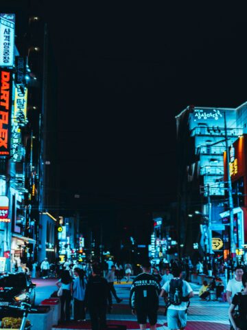 Bright neon signs illuminate Seoul city streets at night with lively pedestrians.