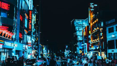 Bright neon signs illuminate Seoul city streets at night with lively pedestrians.