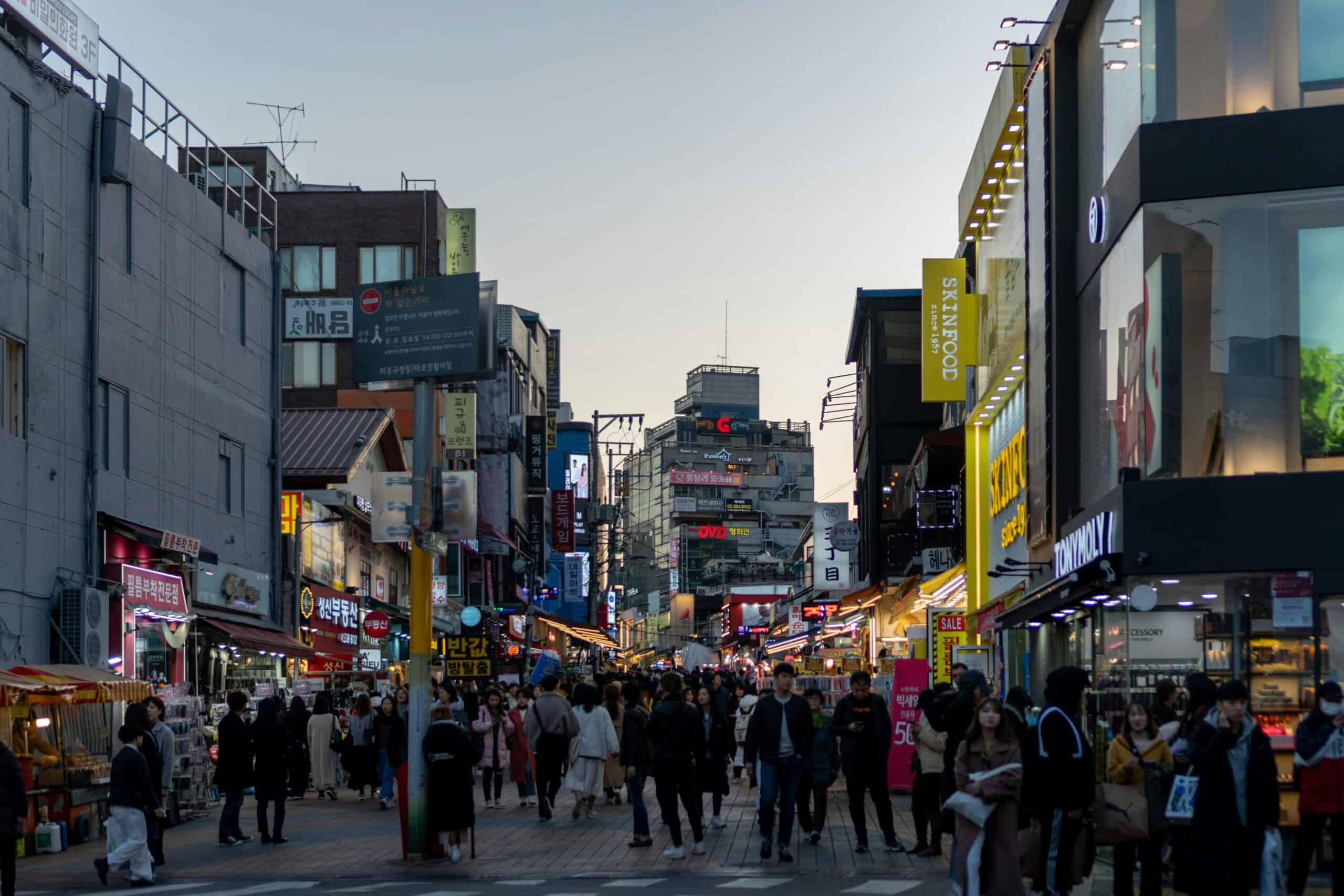 Bustling night market in Seoul with colorful signs and pedestrians.