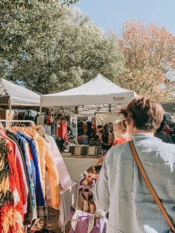 Vibrant outdoor market scene in Seoul with shoppers browsing clothing and accessories.
