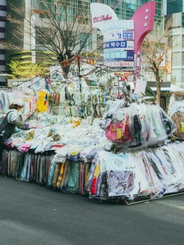Vintage clothing street market in Seoul, Korea, showcasing diverse apparel stalls and shoppers.