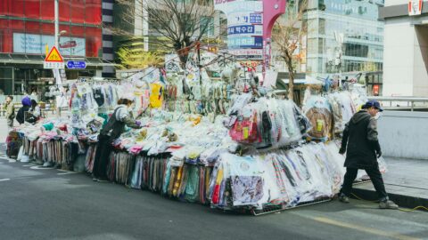 Vintage clothing street market in Seoul, Korea, showcasing diverse apparel stalls and shoppers.